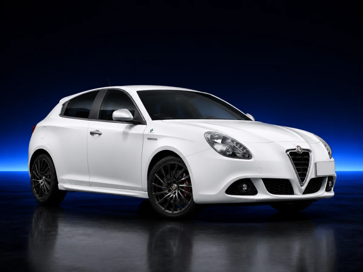 White Alfa Romeo Giulietta 940 on a deep navy and cobalt studio background.