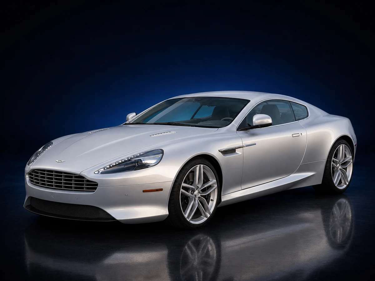 Silver Aston Martin DB9 VH1 facelift coupé on a deep navy and cobalt studio background.
