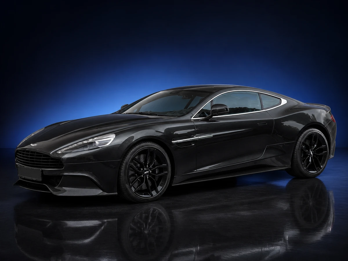 Black Aston Martin Vanquish II coupé on a deep navy and cobalt studio background.