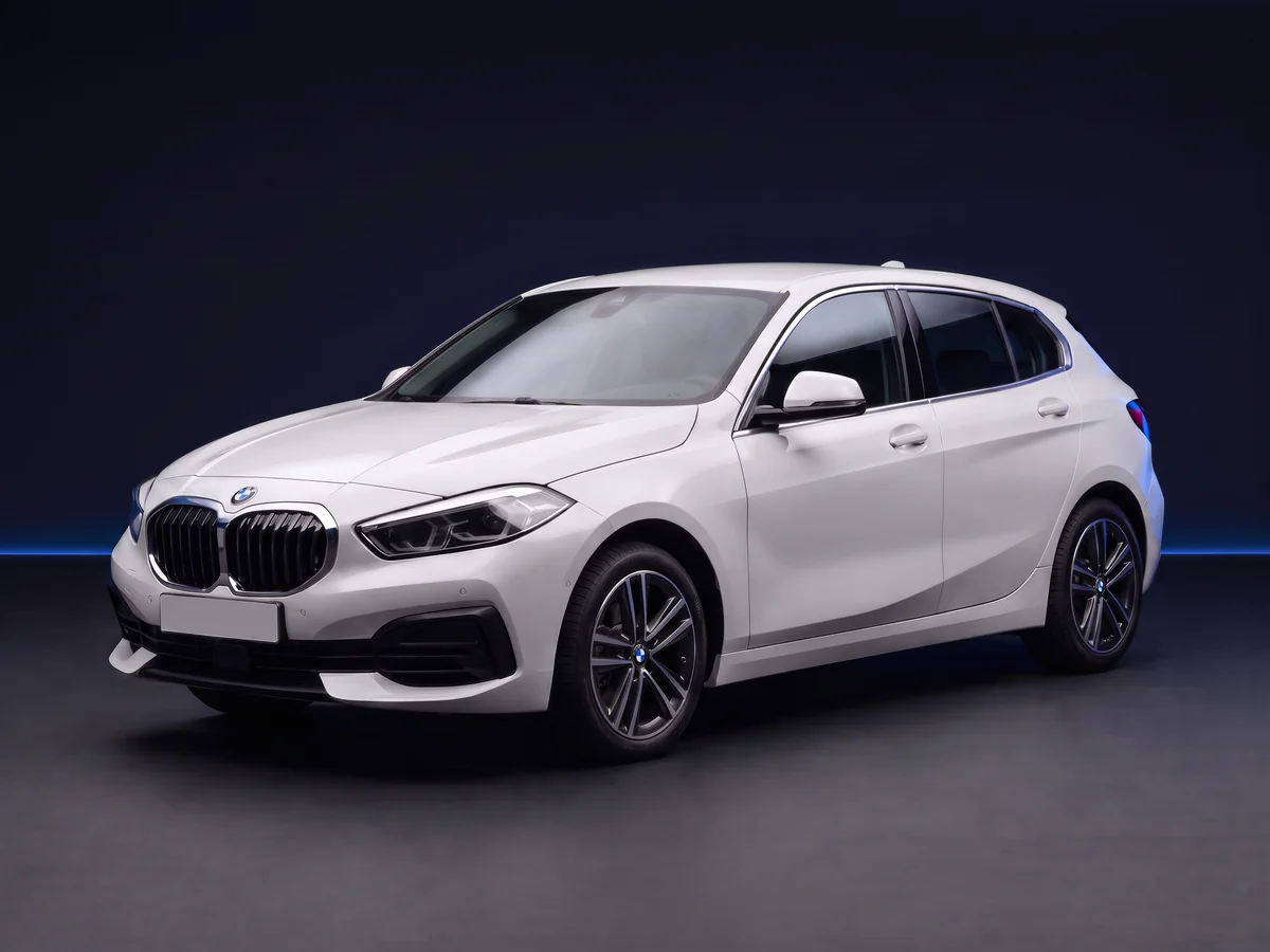 White BMW 1 Series F40 120i hatchback on a deep navy and cobalt studio background.