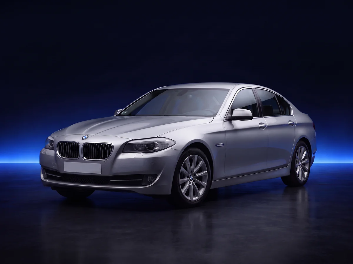 Silver BMW 5 Series F10 saloon on a deep navy and cobalt studio background.
