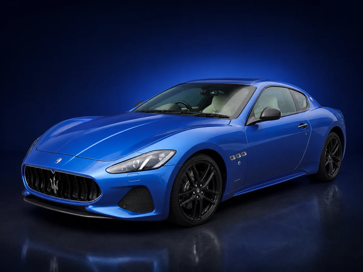 Blue Maserati GranTurismo M145 Sport coupé on a deep navy and cobalt studio background.