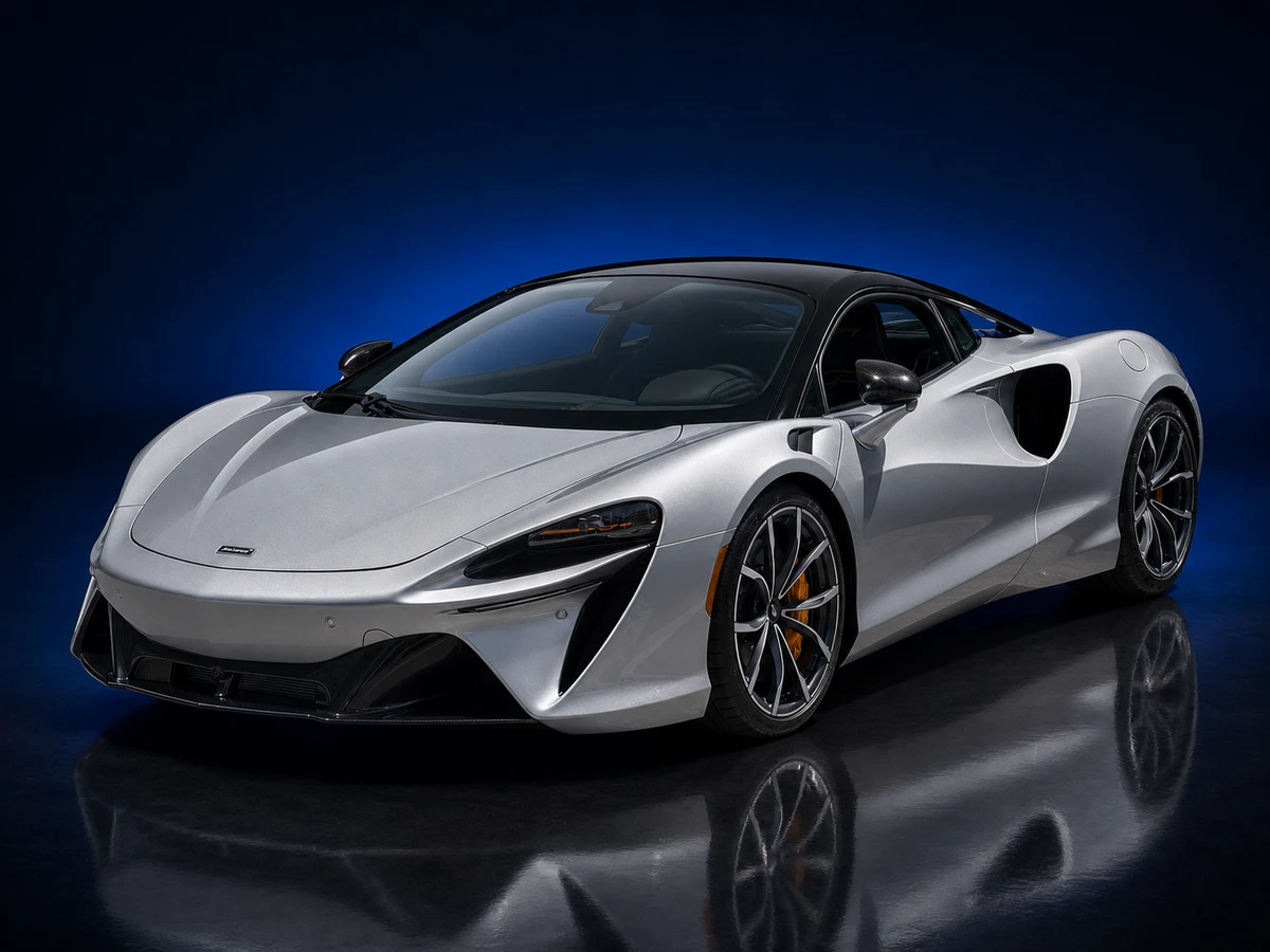 Silver McLaren Artura coupé on a deep navy and cobalt studio background.