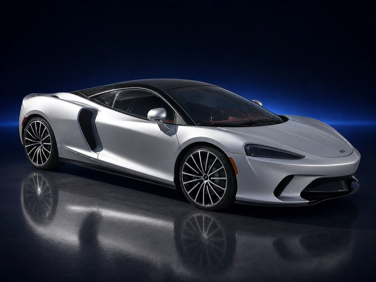 Silver McLaren GT grand tourer on a deep navy and cobalt studio background.