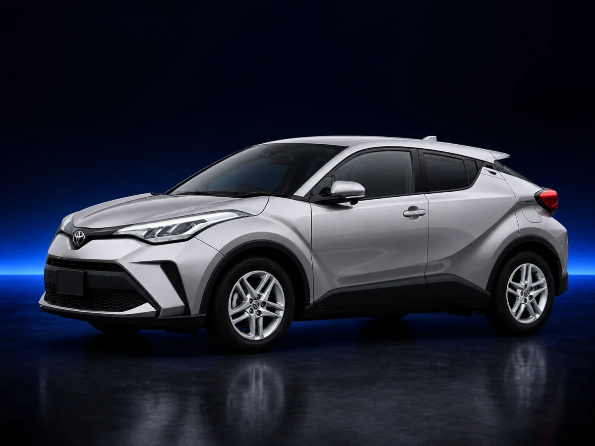 Silver Toyota C-HR AX10 facelift on a deep navy and cobalt studio background.